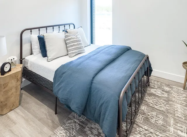 a bed sitting in a bedroom next to a window with lamp