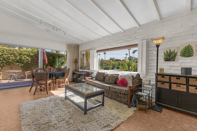 a living room with furniture a rug potted plant and a large window