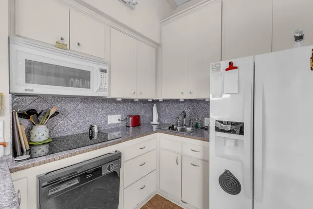 a kitchen with white cabinets and white appliances