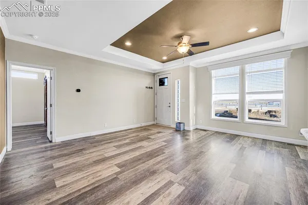 an empty room with wooden floor ceiling fan and windows