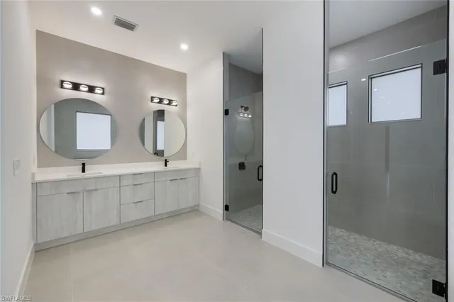 a bathroom with a double vanity sink mirror and shower