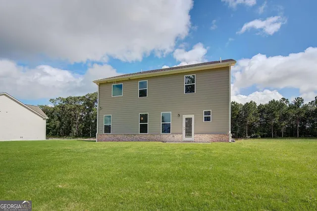 a front view of house with yard and trees in the background