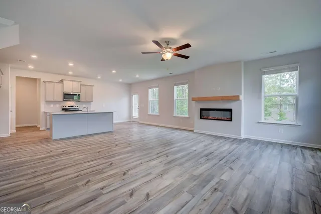 an empty room with wooden floor a fireplace and a kitchen