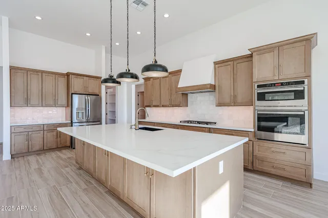 a kitchen with stainless steel appliances a stove a sink a microwave a center island and wooden floor