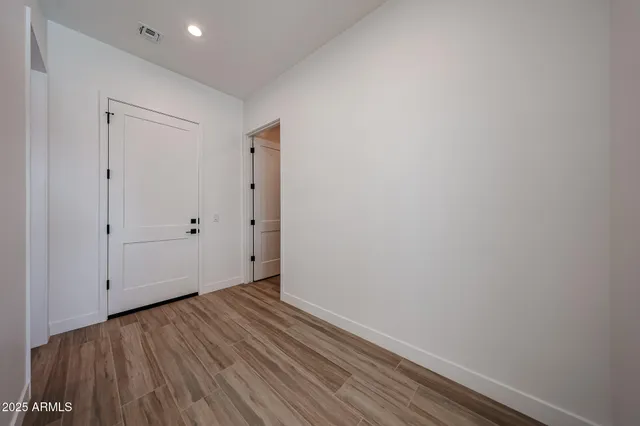 a view of a hallway with wooden floor and a bathroom