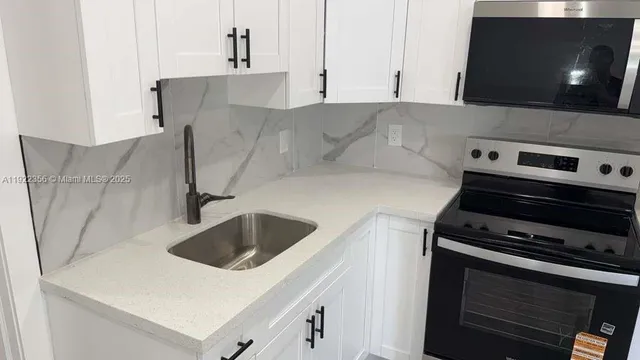 a kitchen with a sink and a stove top oven with granite countertops