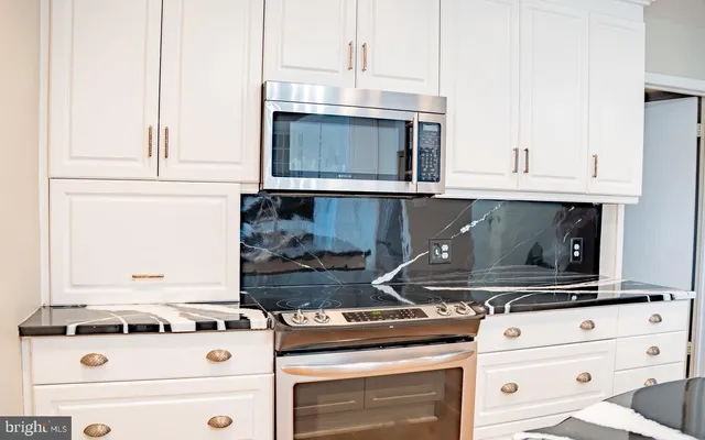 a stove top oven sitting inside of a kitchen and white cabinets