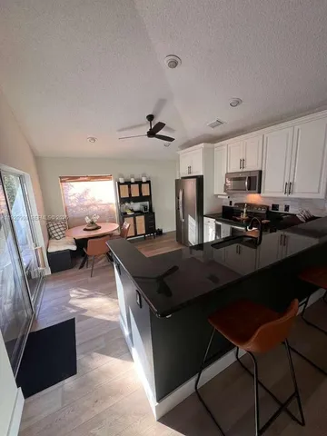 a kitchen with stainless steel appliances granite countertop a stove a refrigerator a sink dishwasher a dining table and chairs with wooden floor