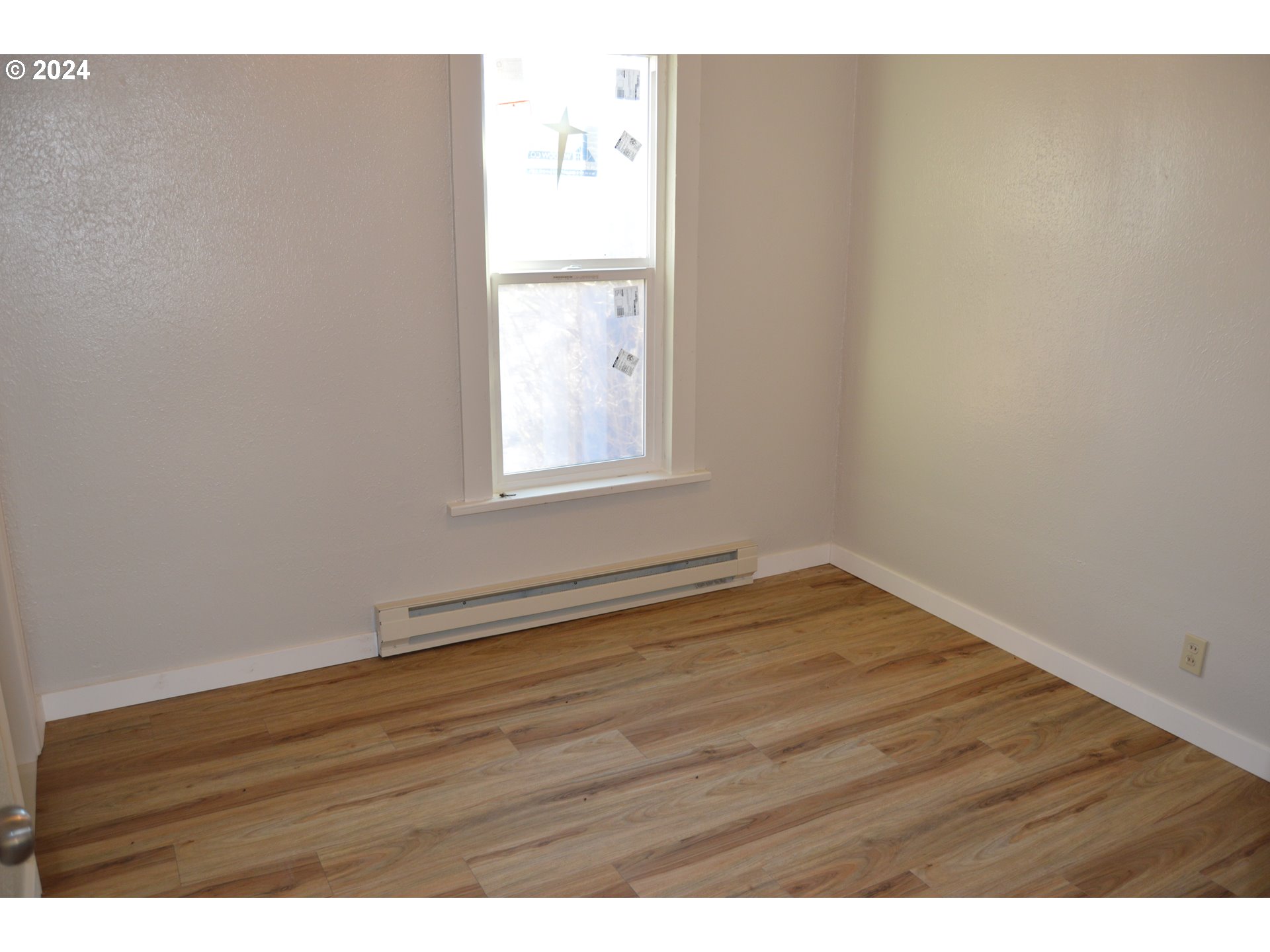 705 Couch Avenue Wallowa, OR 97885 - Photo 22 of 35 a view of an empty room with wooden floor and a window