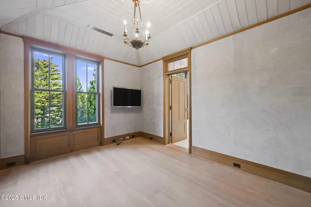 a view of an empty room with a window and hardwood floor