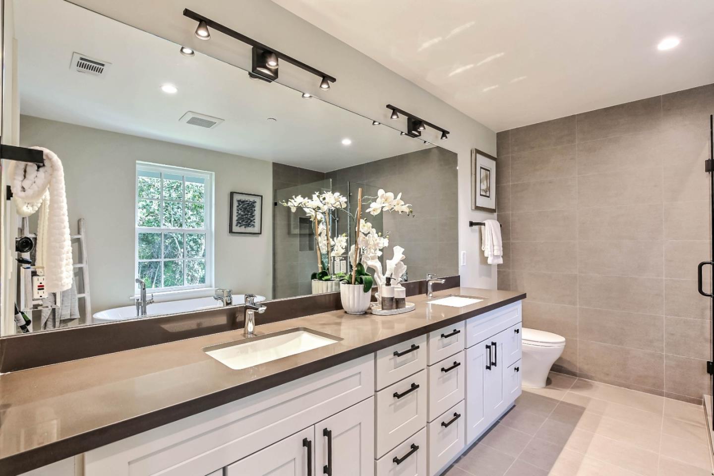 269 Willow Road Menlo Park, CA 94025 - Photo 13 of 26 a bathroom with double vanity sinks a large mirror and a shower