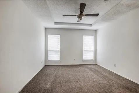 an empty room with a window and a fan
