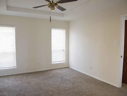 an empty room with a chandelier fan and windows