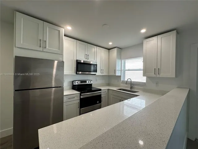 a kitchen with granite countertop a refrigerator a sink a stove a microwave and island