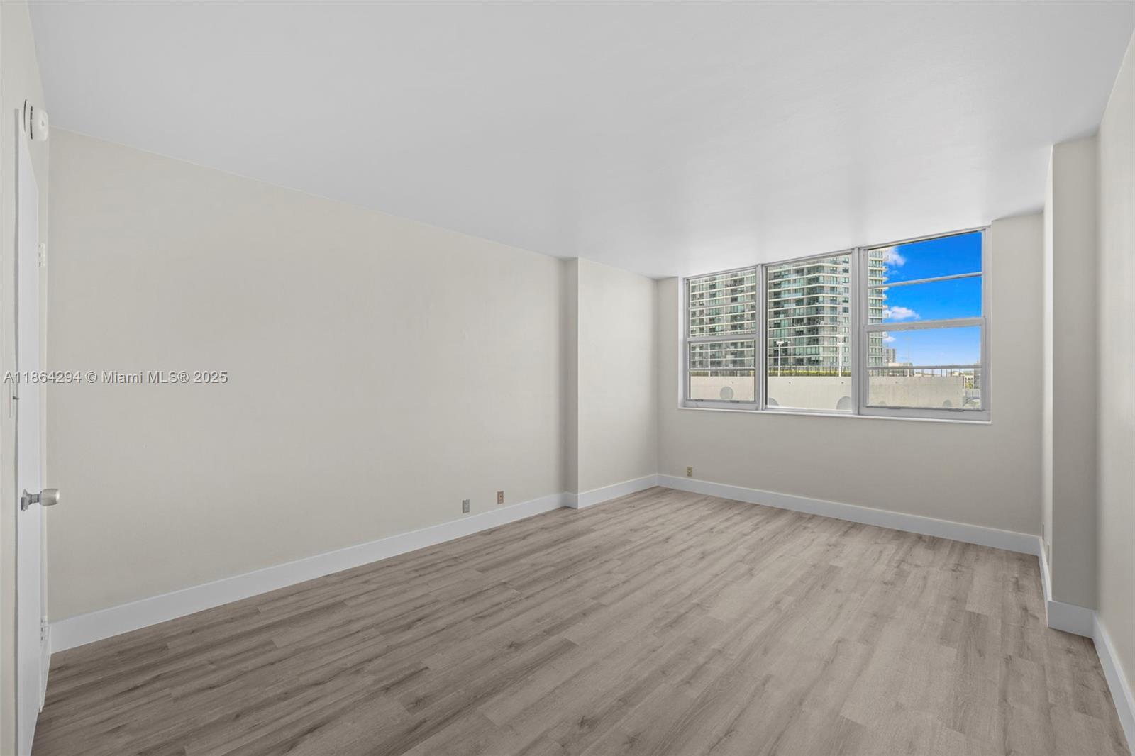 3301 Northeast 5th Avenue, Unit 1018 Miami, FL 33137 - Photo 8 of 24 a view of an empty room with wooden floor and a window
