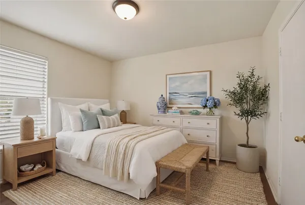 a bedroom with a large bed and a potted plant