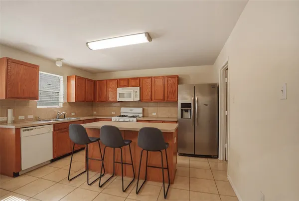 a kitchen with stainless steel appliances granite countertop a stove top oven a sink a dining table and chairs