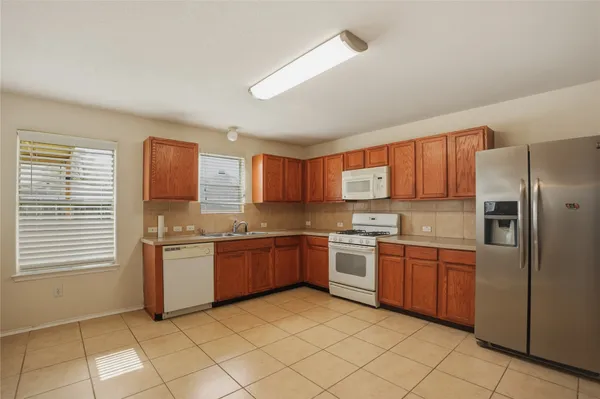 a kitchen with stainless steel appliances granite countertop a stove top oven a sink dishwasher and a refrigerator