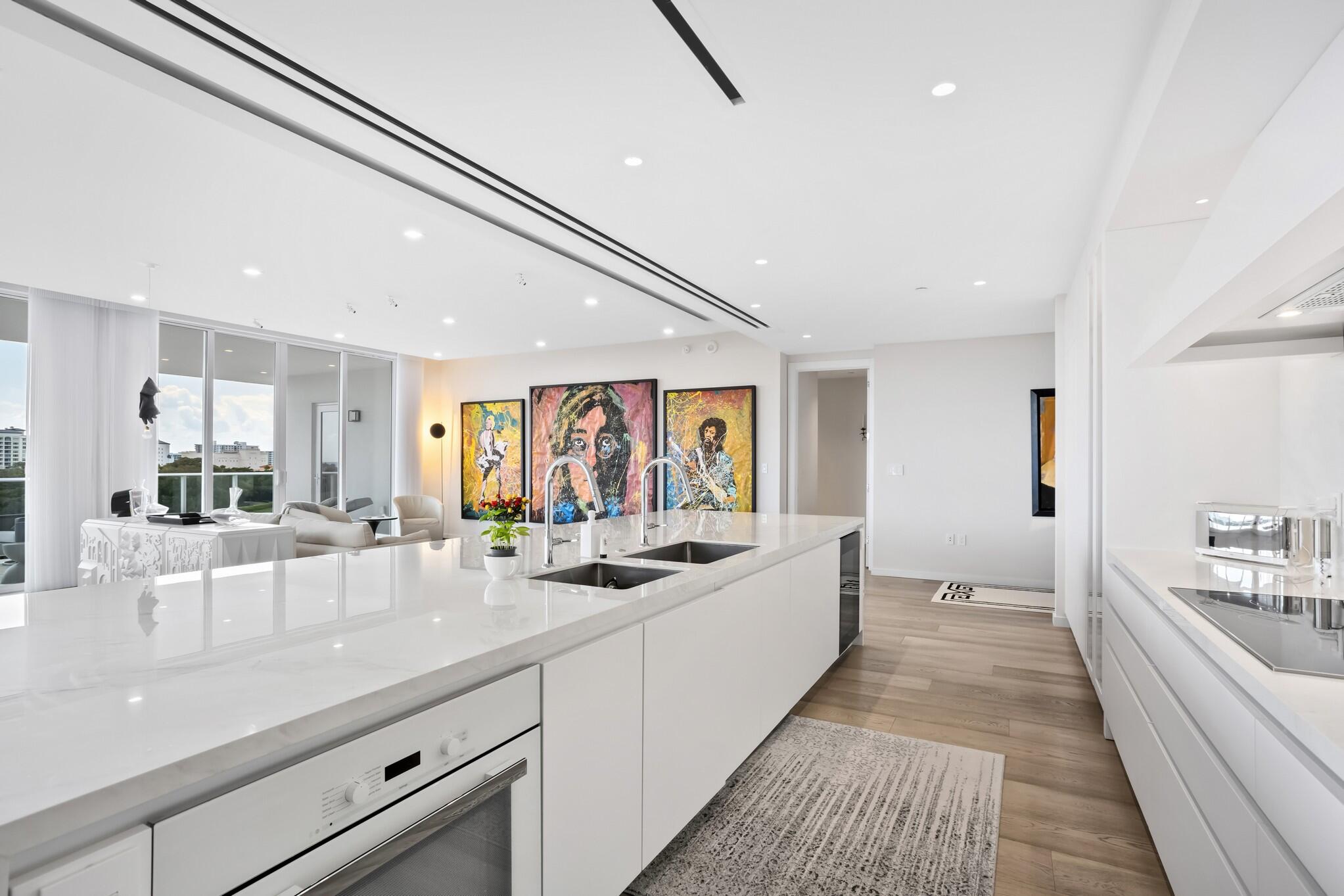 200 Southeast Mizner Boulevard, Unit 717 Boca Raton, FL 33432 - Photo 12 of 66 a large white kitchen with stainless steel appliances kitchen island a large counter top and a fireplace