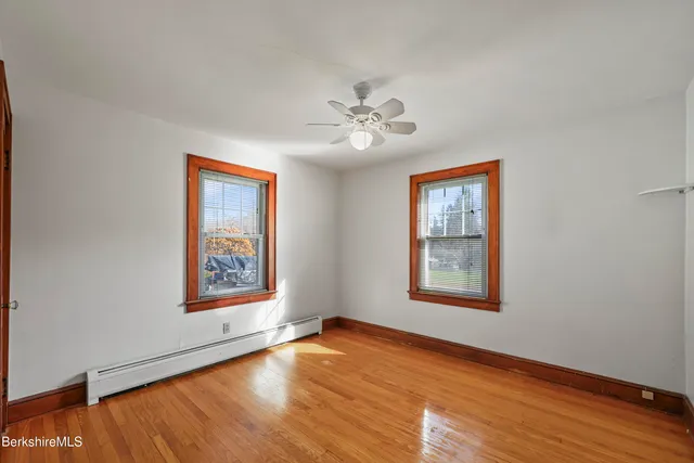 a view of an empty room with a window and wooden floor