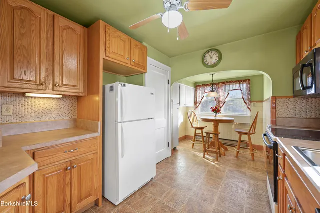 a kitchen with stainless steel appliances granite countertop a refrigerator a sink dishwasher a dining table and chairs with wooden floor