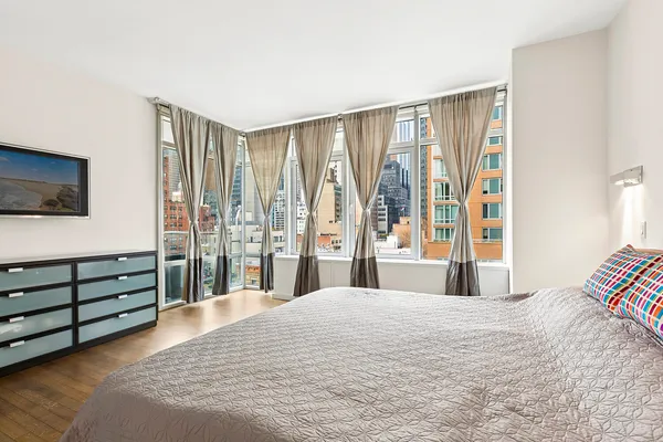 a bedroom with a large bed and a flat tv screen on dresser