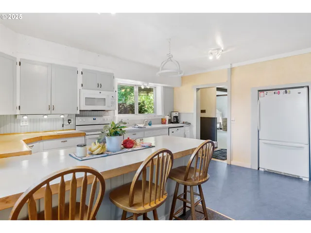a kitchen with stainless steel appliances granite countertop a dining table chairs refrigerator sink and cabinets