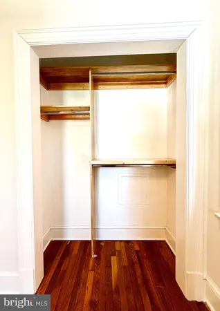 a hallway with white cabinets and wooden floor