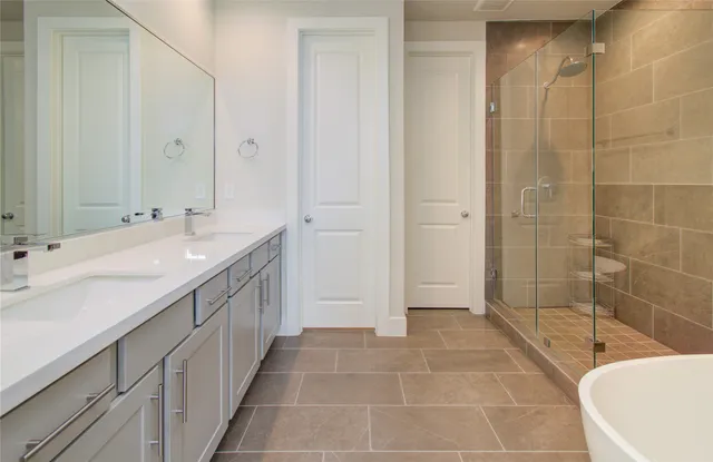 a bathroom with a double vanity sink a toilet and shower