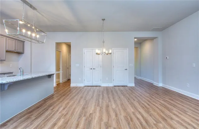 an empty room with wooden floor chandelier fan and windows