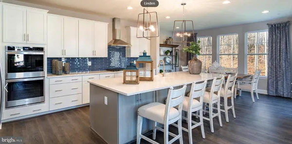 a kitchen with a dining table chairs stainless steel appliances and windows