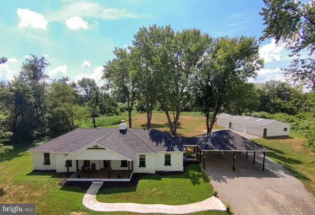 a aerial view of a house with swimming pool and trees in the background