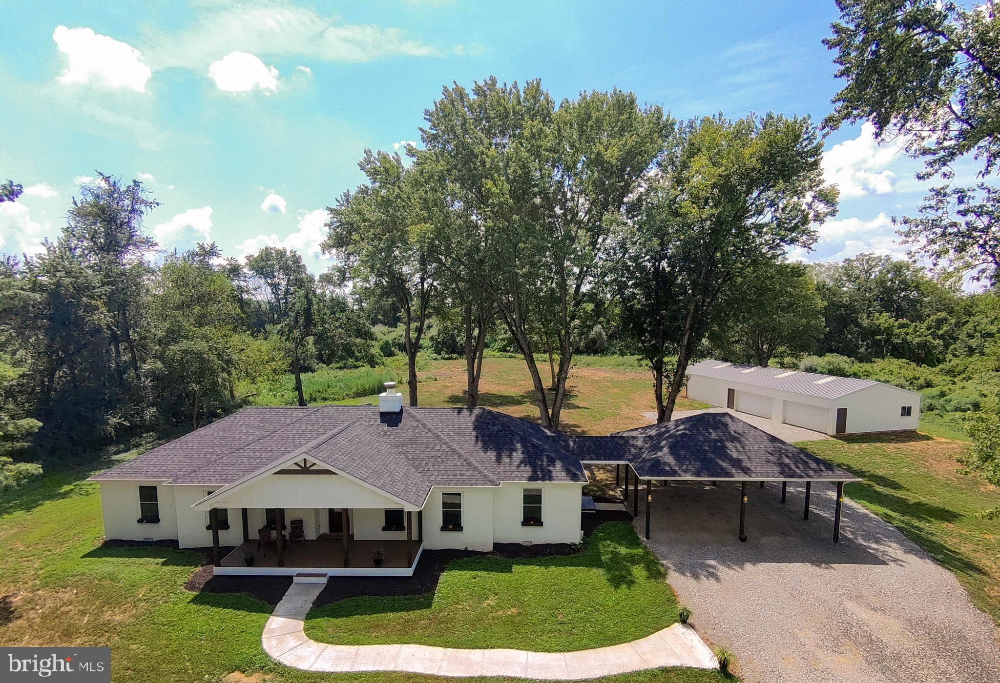 a aerial view of a house with swimming pool and trees in the background