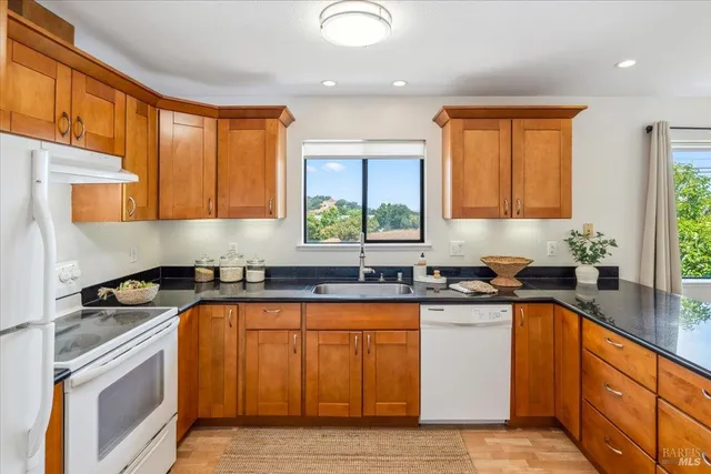 a kitchen with granite countertop a sink stove top oven and cabinets