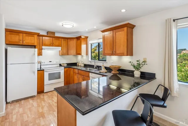 a kitchen with stainless steel appliances granite countertop a sink a stove and a refrigerator
