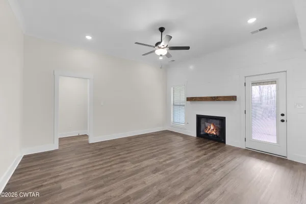 a view of empty room with wooden floor fireplace and fan