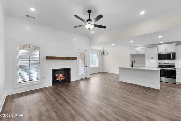 a view of an empty room with kitchen and fireplace