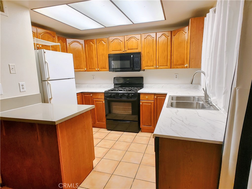 a kitchen with a sink a stove top oven a counter space and a window