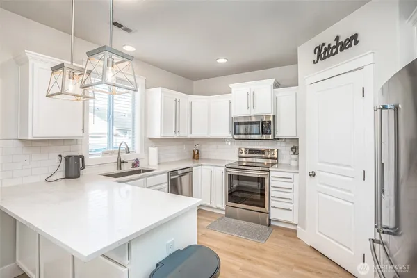 a kitchen with a sink a stove a refrigerator and white cabinets