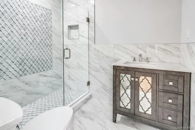 a bathroom with a granite countertop toilet a mirror and shower