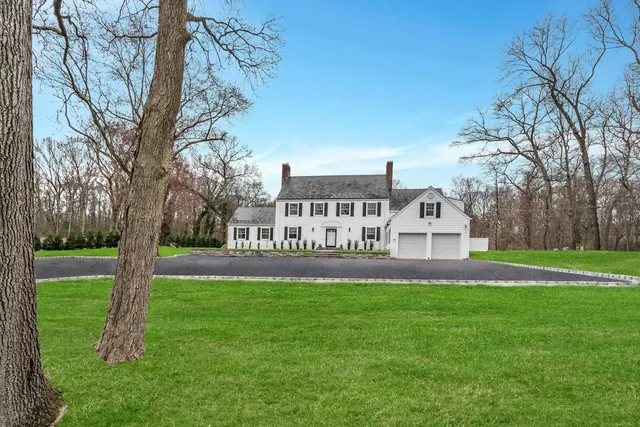 a view of a white house with a big yard and large trees