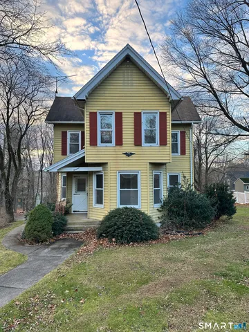 a view of a yard in front of a house with plants and large trees