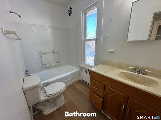 a bathroom with a granite countertop toilet sink and mirror