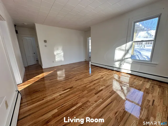 a view of an empty room with wooden floor and a window