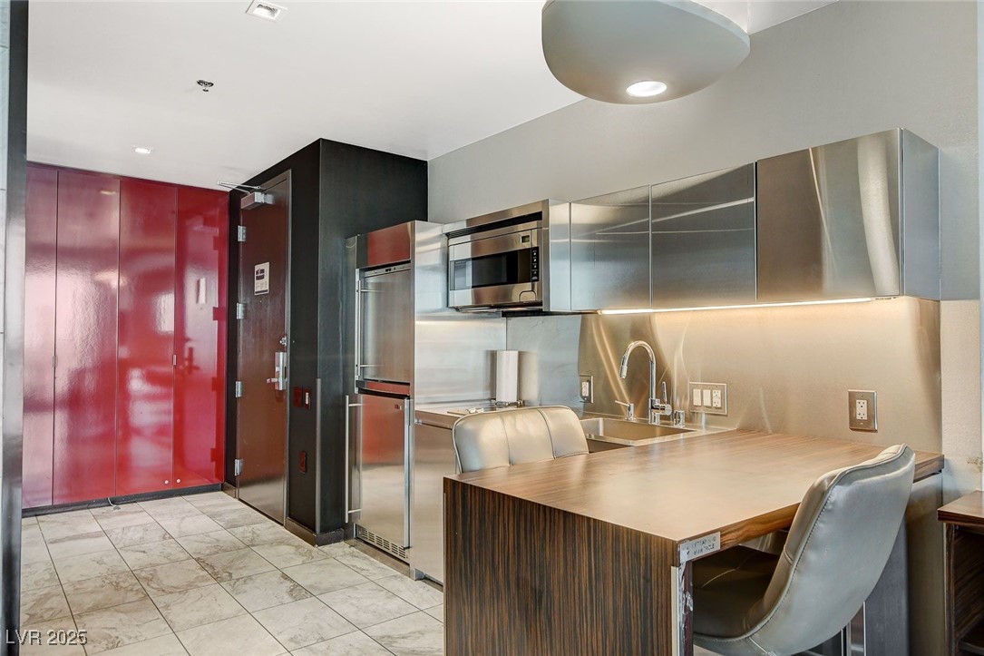 4381 West Flamingo Road, Unit 2204 Las Vegas, NV 89103 - Photo 14 of 27 Kitchen with appliances with stainless steel finishes, light marble finish flooring, a breakfast bar, and light countertops