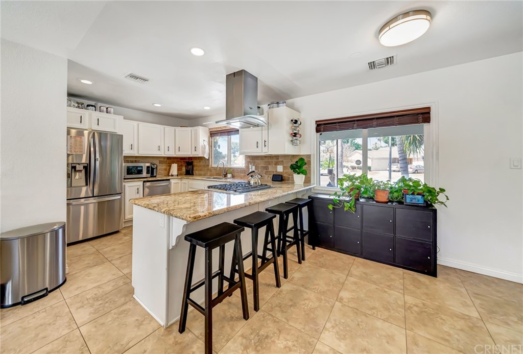 6720 Kurl Way Reseda, CA 91335 - Photo 9 of 40 a kitchen with stainless steel appliances a table chairs refrigerator and microwave