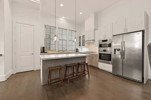 a kitchen with kitchen island a counter top space a sink stainless steel appliances and cabinets