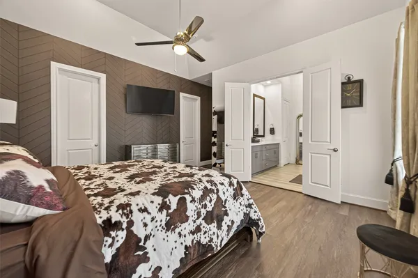 a spacious bedroom with a bed and dresser with wooden floor