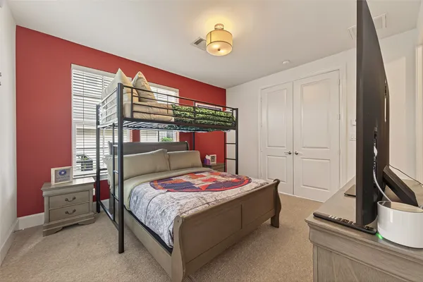 a bedroom with a bed and a flat tv screen on dresser