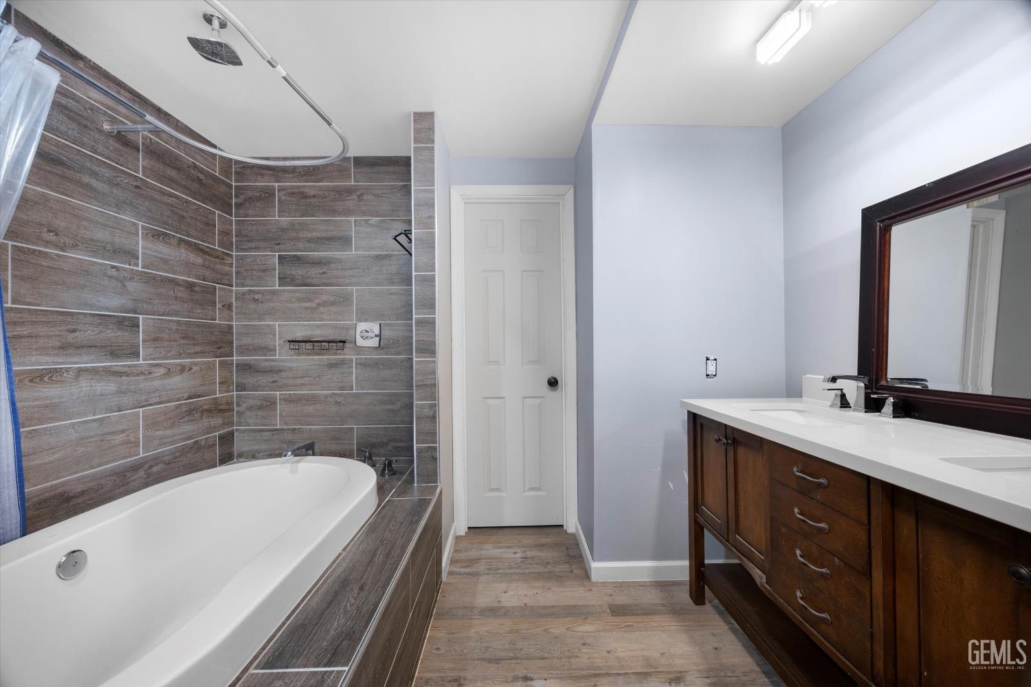 Undisclosed Address Bakersfield, CA 93305 - Photo 16 of 33 a bathroom with a double vanity sink a large mirror and a bathtub